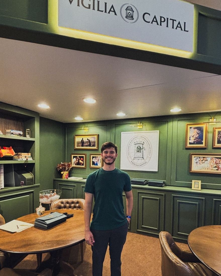 Marcos Condé no evento de lançamento da Vigilia Capital, em uma sala verde com a placa da marca acima